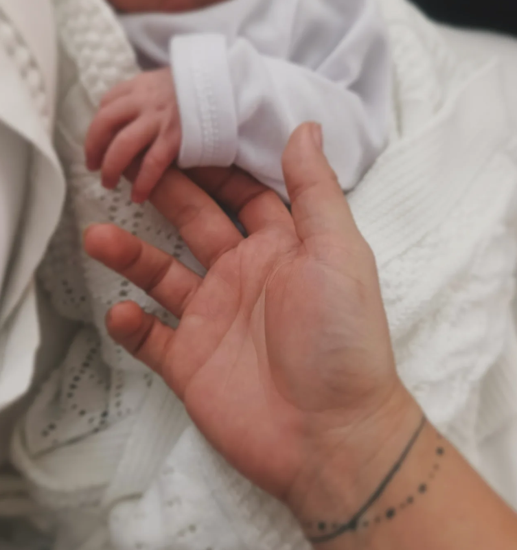 Doula sosteniendo la tierna mano de un recién nacido